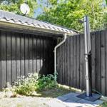 Außen-Dusche neben schwarzem Holzzaun und Gebäude mit Dach.