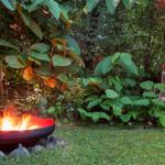 Ein brennender Feuerkessel im Garten mit Stuhl und üppiger Vegetation.