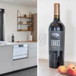 Küche mit Fenster und Waschmaschine. Flasche Wein und Pfirsiche auf Tisch.