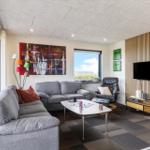 Wohnzimmer mit Sofa, Sessel und Fernseher an Holzwand