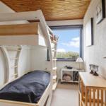 Zimmer mit Doppelstockbett, Fenster mit Aussicht und Schreibtisch.