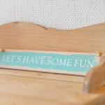 Holzbank mit Schild: LETS HAVE SOME FUN an Wand