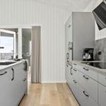 Moderne Küche mit grauen Schränken, Holzboden und Blick auf Balkon.
