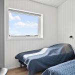 Zimmer mit zwei Betten, Fensterblick und Wandlampe.