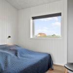 Schlafzimmer mit Bett, Fenster und Stuhl. Blick auf Dach und Himmel.