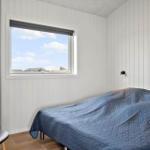 Schlafzimmer mit Bett, Fenster und Stuhl.