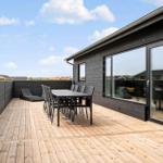 Terrasse mit Tisch und Stühlen, Holzboden und schwarzer Holzwand.