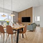 Essbereich mit Tisch und Stühlen, Wohnbereich mit Sofa und Fernseher, Holzfußboden und große Fenster.