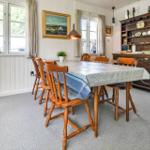 Esszimmer mit Holztisch, Stühlen und Schrank. Fenster, Wandbilder und Teppichboden.