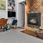 Raum mit Kamin, Fernseher, Bücherregal und Holztisch.