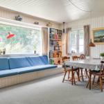 Ein Raum mit blauer Sitzbank, Essbereich und Bücherregal an der Wand.