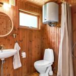 Bad mit Dusche, Toilette und Waschbecken an Holzwand.