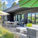 Deck with seating, table, grill, and umbrellas. Modern house with glass doors.