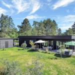 Modern villa with terrace, garden, and view of forest.