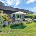 Modern villa with large garden, terrace, and seating areas under umbrellas.