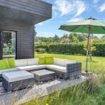 Deck with seating, umbrella, and view of green lawn.