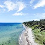 Beach with clear water and green vegetation along the coast.