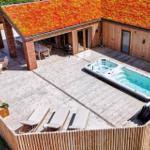 Haus mit begrüntem Dach, Whirlpool und Terrasse mit Sitzgelegenheiten.