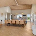 Großes Wohn- und Esszimmer mit Holzboden, Essbereich und Küche im Hintergrund.