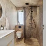 Badezimmer mit Dusche, Waschbecken und Toilette. Marmorwände und -boden.