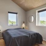 Schlafzimmer mit Bett, zwei Fenstern und runden Wandspiegeln.