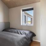 Schlafzimmer mit Bett, Fenster und Holzdecke.