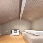 Schlafzimmer mit Bett, Holzboden und schrägem Dach mit eingebauten Lichtern.