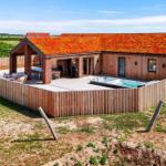 Moderne Villa mit Holzfassade und rotem Dach, umgeben von einer Terrasse mit Pool und Garten.