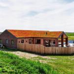 Moderne Villa mit grüner Dachdeckung, Holzterrasse und Garten. Poolbereich mit Liegestühlen.