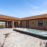 Moderne Villa mit Whirlpool, Holzterrasse und grüner Dachfläche.