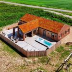 Moderne Villa mit grüner Dachdeckung, Terrasse und Whirlpool im ländlichen Umfeld.