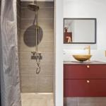 Bad mit Dusche, Waschbecken und Toilette. Rot lackierter Schrank mit goldfarbenem Waschbecken.