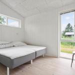 Schlafzimmer mit Bett, Stuhl und Fenstern zur Außenseite.