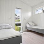 Zimmer mit zwei Betten, weißen Wänden und Fenstern mit Blick auf Gras.
