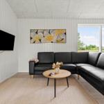 Ein Wohnzimmer mit schwarzem Sofa, runden Tisch und Wandbild.