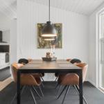 Essbereich mit Holztisch, Ledersitzen und Wandbild. Küche im Hintergrund. Durchgang zu Wohnbereich.