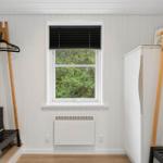 Zimmer mit Fenster, Gardine, Heizkörper und Kleiderständer