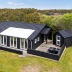 Moderne schwarze Villa mit Terrasse und Garten. Umgeben von Wald und Grünflächen.
