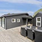 Schwarze Holzhütte mit Terrasse und Sitzgruppe im Freien.