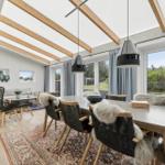 Essbereich mit Tisch, Stühlen und Fenstern. Decke mit Holzbalken und Hängelampen.