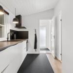 Moderne Küche mit weißen Schränken, dunklem Arbeitsplatz und Fenster mit Pflanze.
