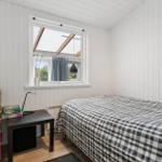 Schlafzimmer mit Bett, Schreibtisch und Fenster mit Blick nach draußen.