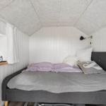 Schlafzimmer mit Bett, Fenster und Wandlampe.