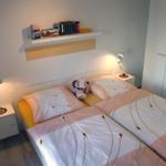 Schlafzimmer mit Doppelbett, Nachttischen und Bücherregal an der Wand.