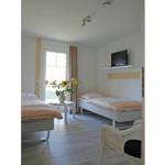 Zimmer mit zwei Betten, Fernseher und Fenster mit Sonnenblumen.