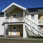 Zweistöckiges Ferienhaus mit weißen Balkonen und Treppe. Hausnummer 28 und 30.