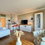 Apartment with bedroom, kitchen, and living area with TV and floral sofa.