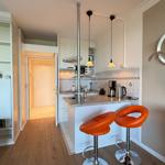 Kitchen with countertop, two orange bar stools, and sink.
