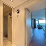 Hallway with view into bedroom and bathroom. Wall clock and hooks visible.