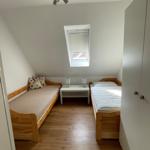 Zimmer mit zwei Betten, Dachschräge, Dachfenster und Holzboden.
